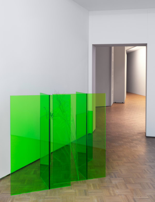 a lime green folded plexiglass formation standing upright within a room.