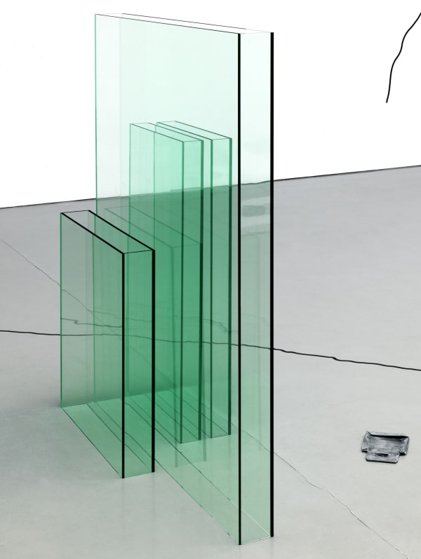 green plexiglass sculptural formations aligned closely next to each other, each one resembling a thin rectangular box-like shape.