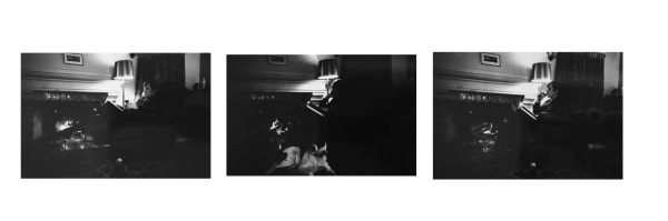 Three mid-sized black and white photographs of the artist Bas Jan Ader sitting, with a book, in a an armchair in a dark room lit up by one standing lamp.