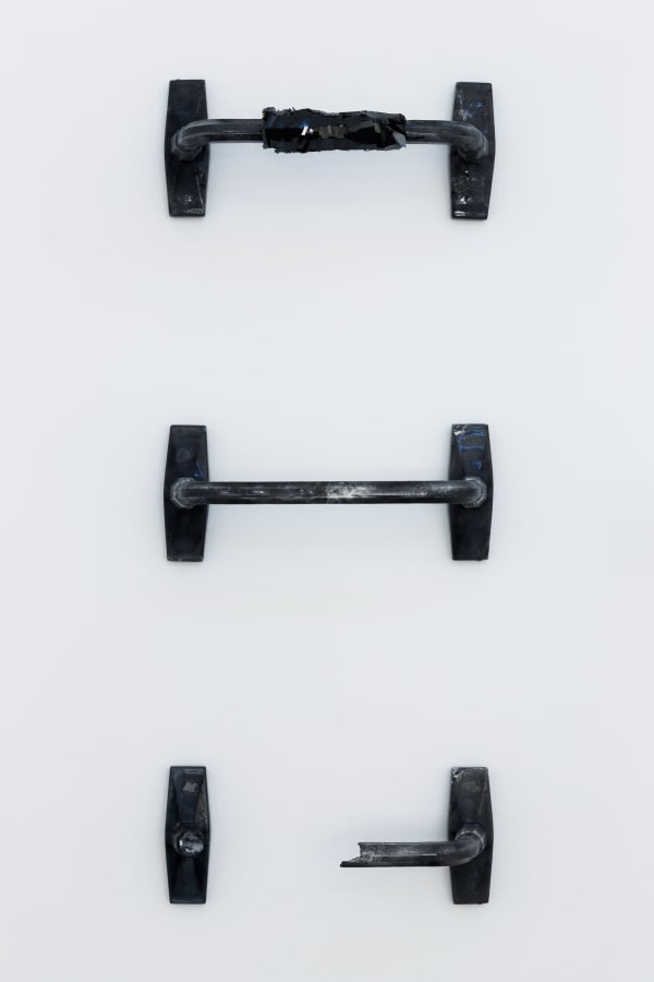 An image of three dumbbell shaped silicone rubber objects against a white wall.
