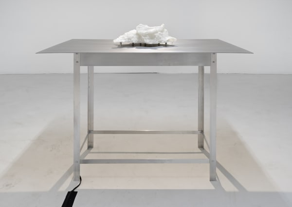 A white sculpture sitting on an aluminum table.