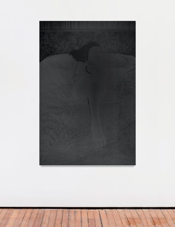 An inkjet print of a shadowy figure on a bed.