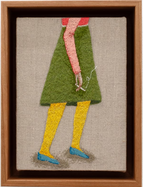 Embroidered figure holding a cigarette, wearing a knee length green skirt and a pink long sleeve top with blue flat shoes.