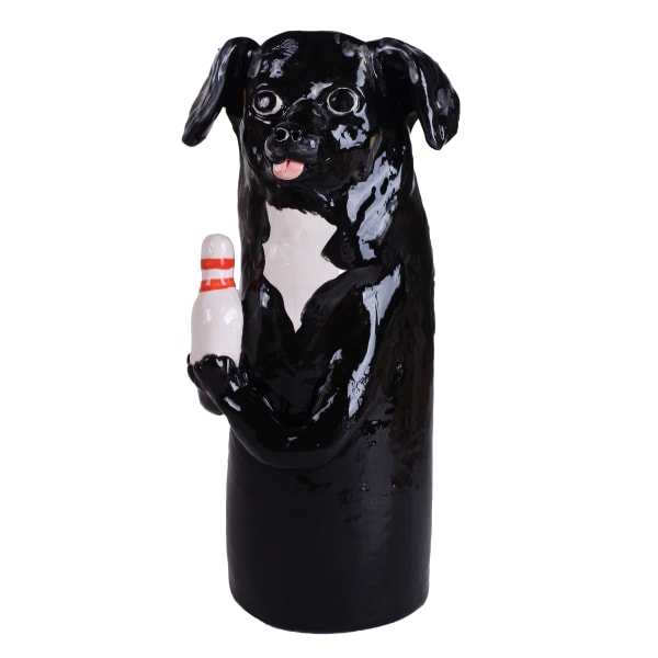 Ceramic vessel of a black dog with floppy ears and its tongue sticking out holding a bowling pin by Katie Kimmel