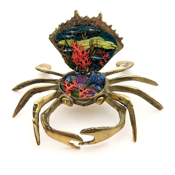 Sculpture of a brass crab with an underwater scene inside of the crab shell