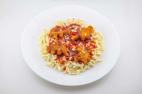 Glass sculpture of a white plate with spaghetti topped with dino nuggets