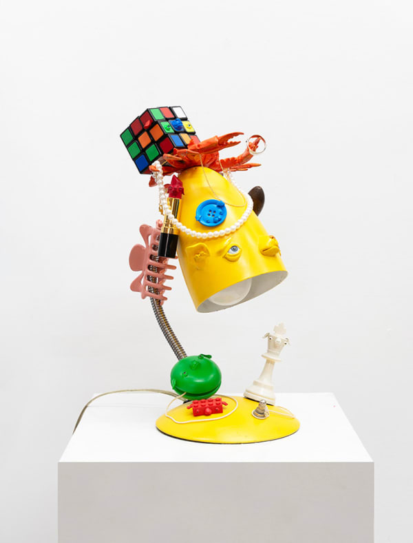 yellow lamp with dog facial features with various items stacked on top also with dog faces