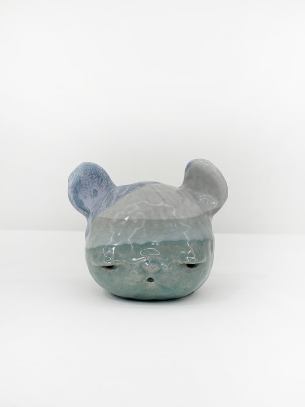 Ceramic sculpture of a bear head with striped blue tones across its head.