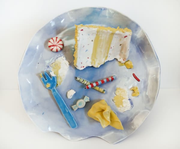 Ceramic plate with a ceramic cake, birthday candles, candies and forks on it.