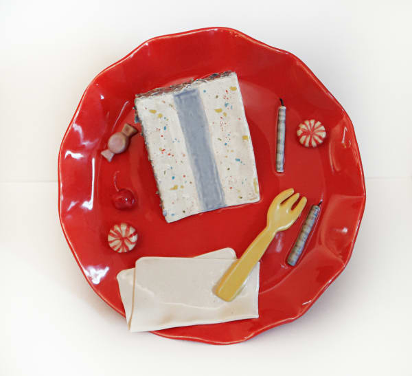 Ceramic plate with a ceramic slice of cake, a fork, a napkin, birthday candles and a candies on it.