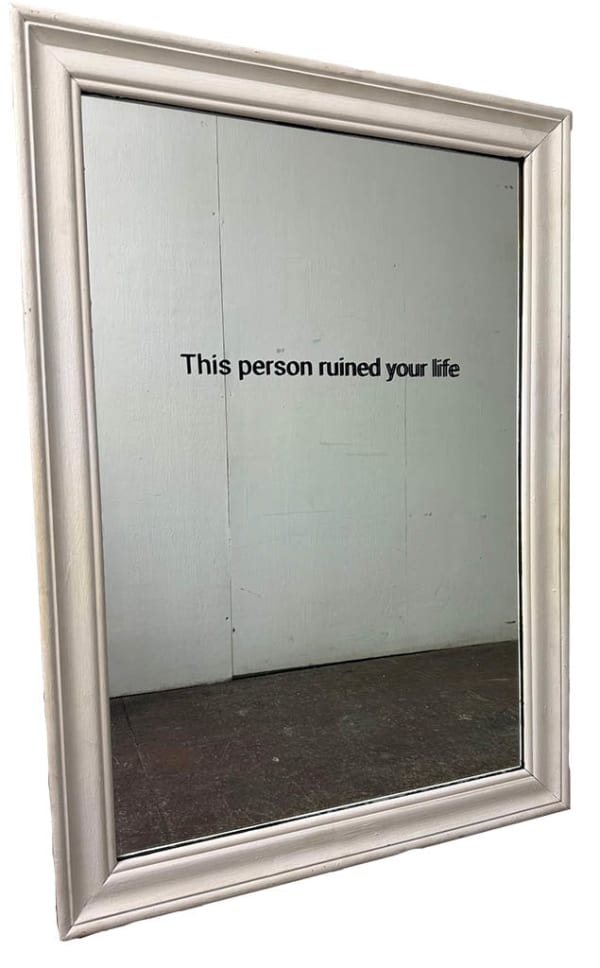 Mirror in a white frame with the words "This person ruined your life" in black text.