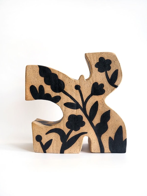 ceramic piece by Jocelyn Tsaih of a brown figure with black flowers on it