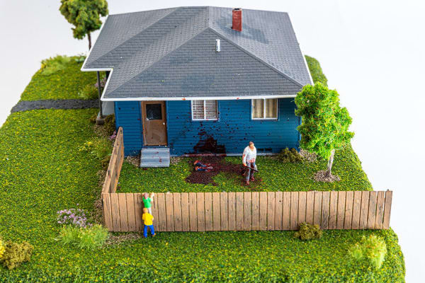 miniature diorama by Abigail Goldman of two boys looking over a fence into the yard burying dead bodies