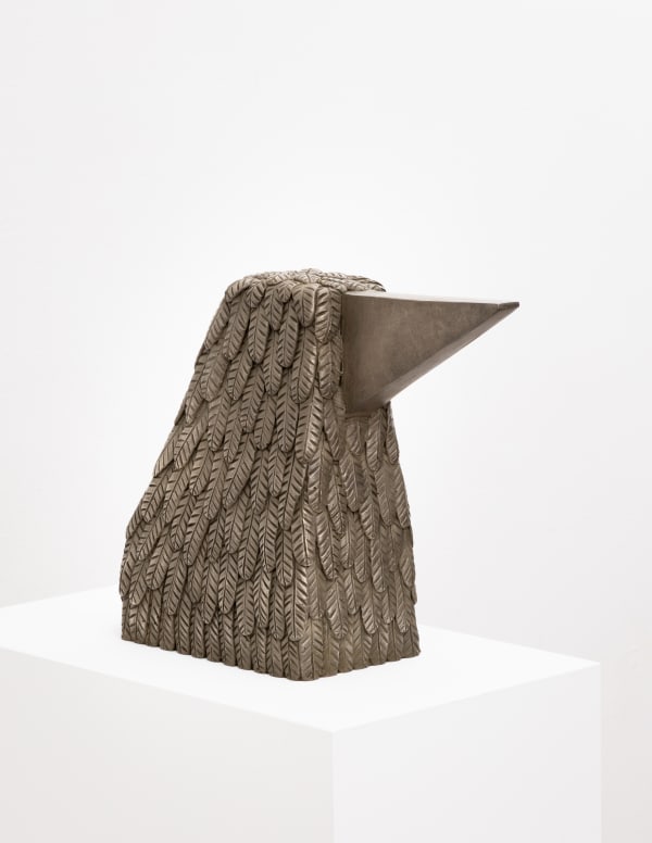 Free-standing bronze sculpture of a form resembling a bird cast with a surface texture resembling feathers with a large triangular beak
