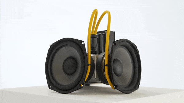 Two small subwoofers connected to yellow wires and metal box.