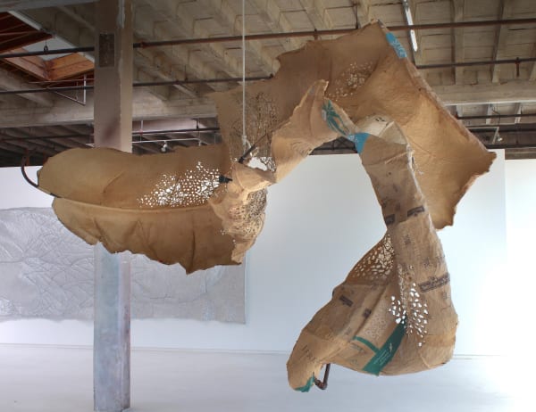 Mixed media sculpture of found objects such as paper bags and poultry netting takes on the form of a giant twisting dead leaf