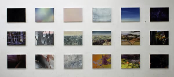 18 small rectangular panels arranged in a grid of three rows and six columns. Each panel has a distinct abstract or landscape scene mostly in shades of black, dark blue and orange. Together the panels make a singular abstract landscape composed of sky on the top row, horizon in the middle, and earth on the bottom row.