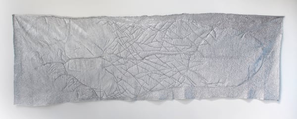 Giant rectangular silver polyester moving mat stitched and formed in areas to resemble the outline of the artist’s foot