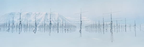 Digital panoramic landscape photograph of a field of antenna with the arctic mountainscape of Svalbard in the background