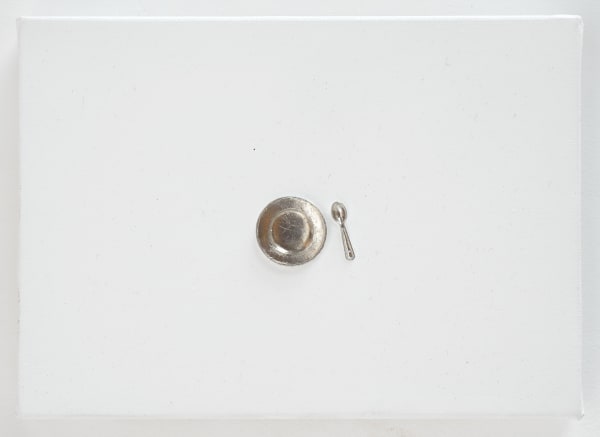 Silver plate on spoon figurines in center of white canvas