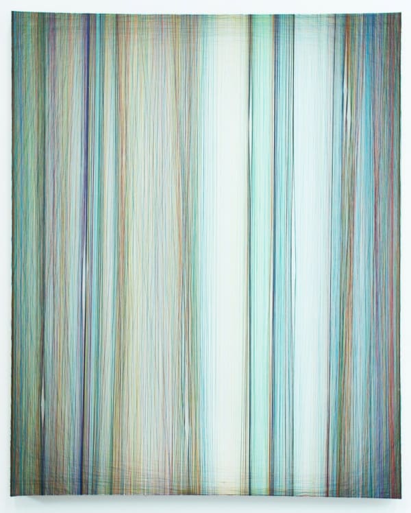 Layers of multi-colored blue green and purple threads strung vertically down a rectangular wooden and plaster panel create the effect of a glowing background
