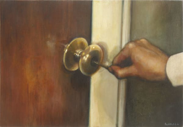 A hand is inserting a key into the round brass doorknob of a wooden door.