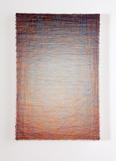 Layers of multi-colored threads strung across a rectangular wooden and plaster panel create the effect of a soft white glowing background enclosed by a dark purple border at the top which fades to a deep orange at the bottom of the frame