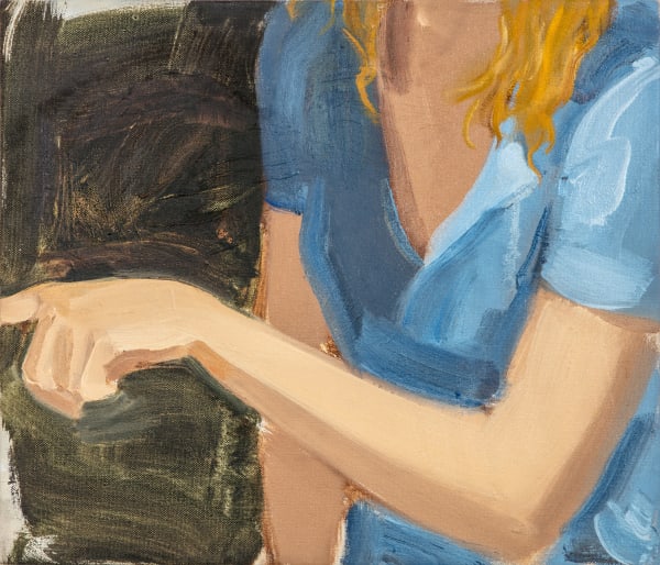 Blonde woman in blue shirt pointing to the left with her left hand. Woman’s head and lower body are cropped out of the composition.