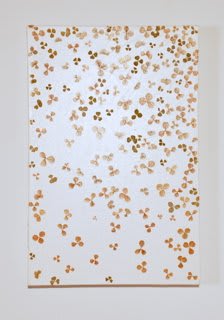 Orange and brown paint applied to white painted canvas with organic material that forms clover shapes of various sizes across the piece