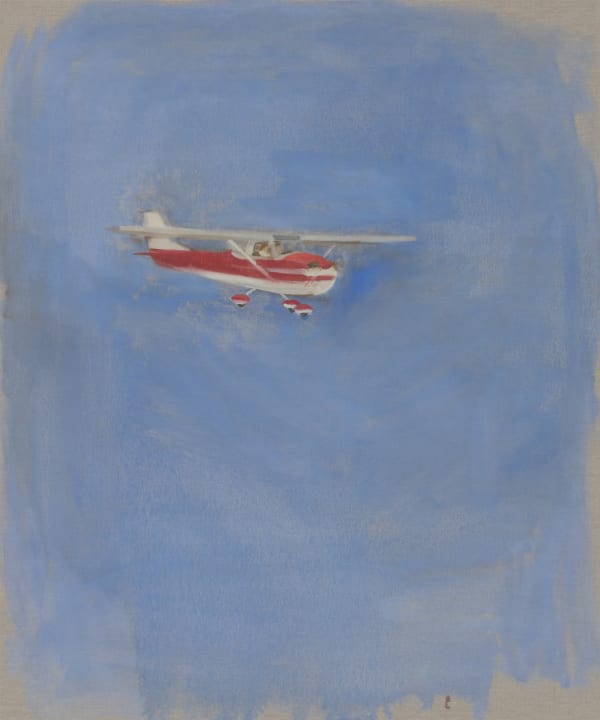 Red and white Cessna plane flies to the right against blue sky and exposed canvas background.