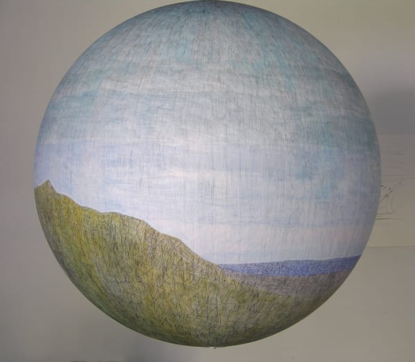 Ballpoint pen drawing with washes of blue purple and green gouache create a hilly seaside landscape on paper which is pasted onto a large fiberglass hanging globe. Throughout the green hills and blue sea various thoughts are scribbled down in all caps