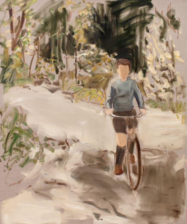 Young faceless boy wearing long socks, shorts and blue shorts bikes towards the viewer on forest path.