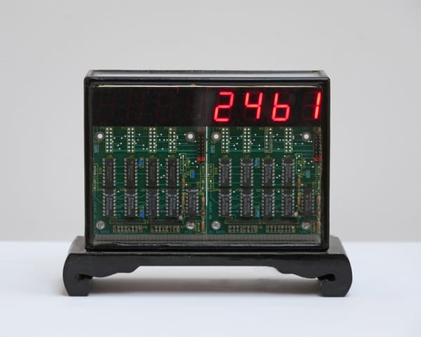 Still image of a digital counter. In this still the counter displays a series of red LED pixels that create the number two thousand four hundred sixty one. The counters green circuit boards are visible and encased by black plastics