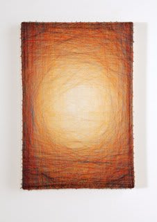 Layers of multi-colored threads strung across a rectangular wooden and plaster panel create the effect of a large glowing yellow center that is enclosed by a gradually more saturated red border