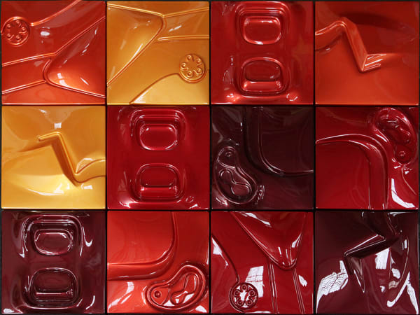 Three-by-four grid of reflective red and orange toned squares with low relief depictions of automotive and anthropomorphic close-up scenes.