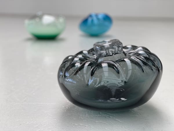 Three glass sculptures arranged on a white floor.