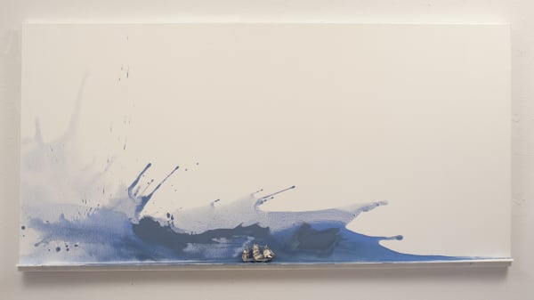 Blue splashes of paint dash across the left edge and along the bottom of a rectangular white canvas. A tiny figurine of a three mast ship is mounted at the bottom center of the piece and is surrounded by blue paint