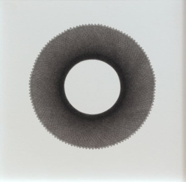 Against white background, a scalloped black ring surrounds white center and becomes dark gray towards its outer perimeter.