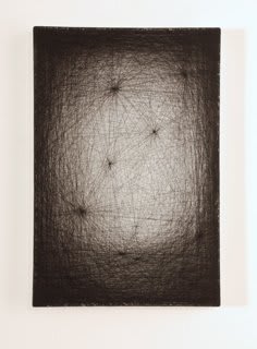 Layers of multi-colored threads strung across a rectangular wooden and plaster panel create the effect of a white glowing center that is enclosed by a thick dark border In the glowing center there are several condensed thread spaces which appear like moon craters