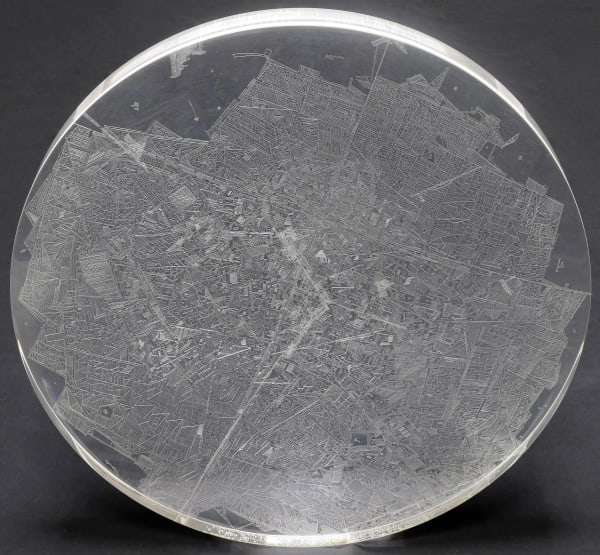 A clear convex disk with etchings set on a dark grey background.