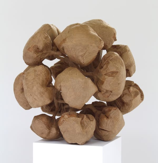 Craft paper sculpture depicts multiple finger print textured ballooned puffs which create a loose image of a pinecone The puffs are connected to each other by various stems which trace back to a central humanoid figure hidden at the center