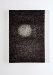 Layers of multi-colored threads strung across a rectangular wooden and plaster panel create the effect of a small white glowing orb in the upper left center of the panel The rest of the piece is a mix of dark gray and black