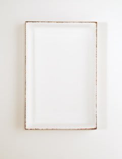 Multi-colored thread strung along the sides of wooden frame bordering white canvas