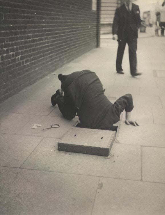 Dora Maar Man looking inside a sidewalk inspection door, London, c. 1935