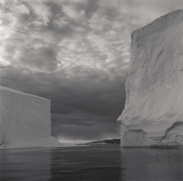 Lynn Davis photograph of two geometric icebergs in Disko Bay, Greenland, with cloudy sky and inky water