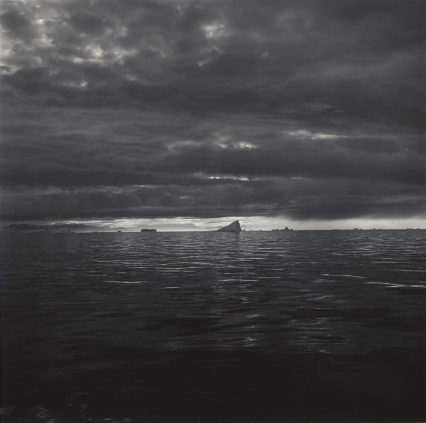 Lynn Davis photograph of iceberg in distance, dark sky and inky water, Disko Bay, Greenland