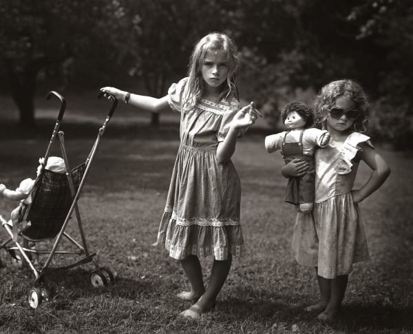 Jessie and Virginia acting as new mothers with baby dolls, stroller and candy cigarette, from the Immediate Family series by Sally Mann