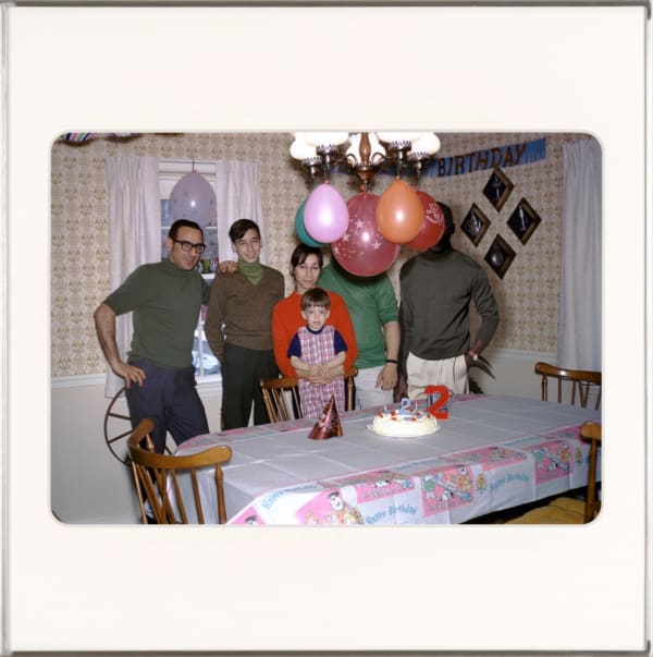 Picture of a family standing around a kitchen table for a child's birthday. By Lee Shulman & The Anonymous Project.