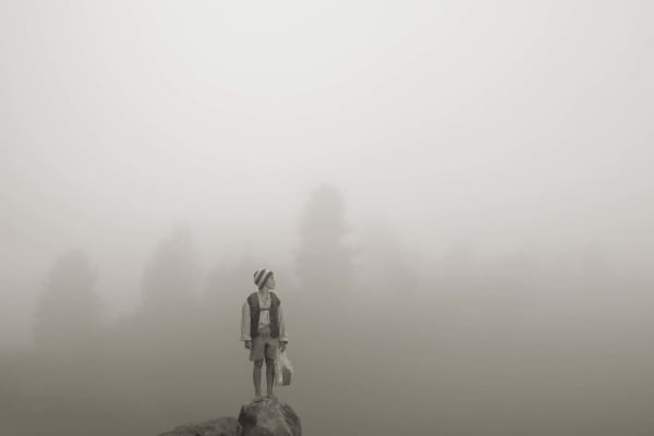 Young boy on mountain top in front of misty landscape, by Erwin Olaf