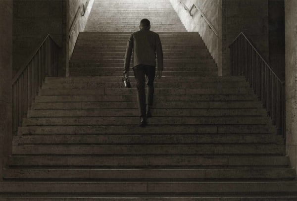man holding camera ascending staircase
